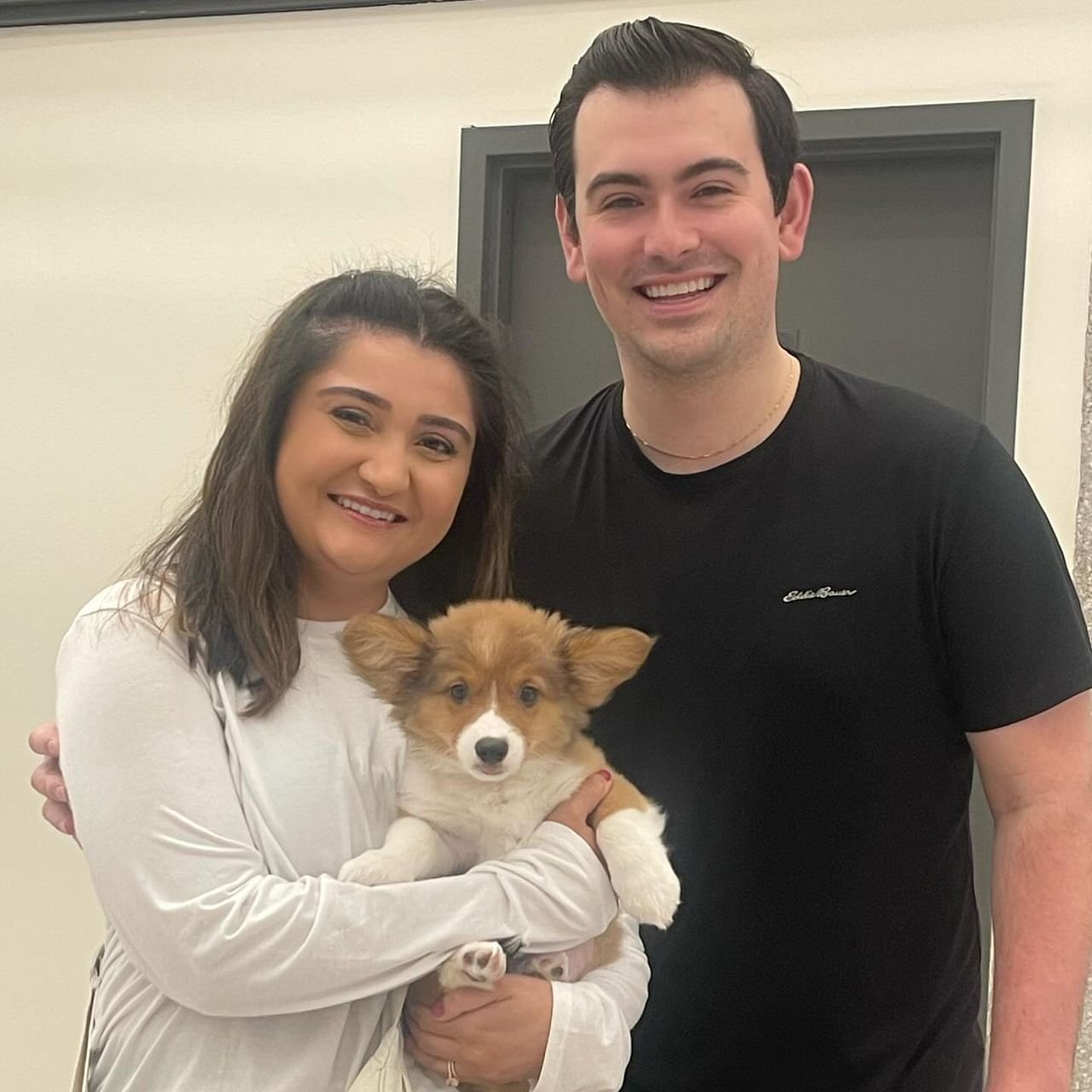 Couple smiling with their new Corgi puppy indoors